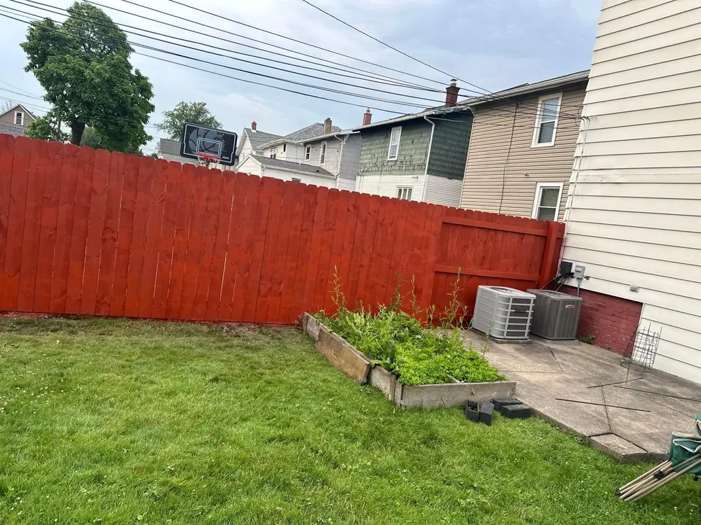 Red-stained privacy fence behind a basketball hoop in Buffalo, NY